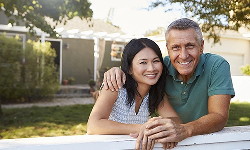 Portrait Of Mature Couple Looking Over Back Yard Fence