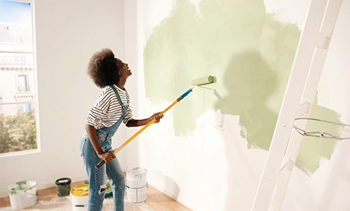 woman painting wall green