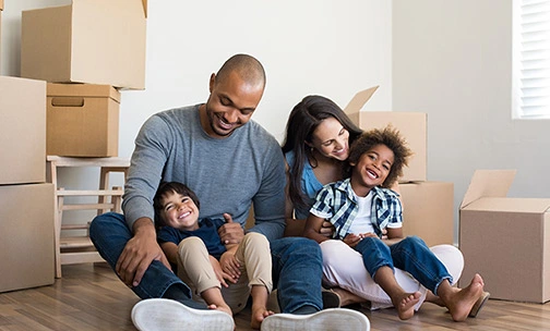 family on the floor while playing in front of moving boxes