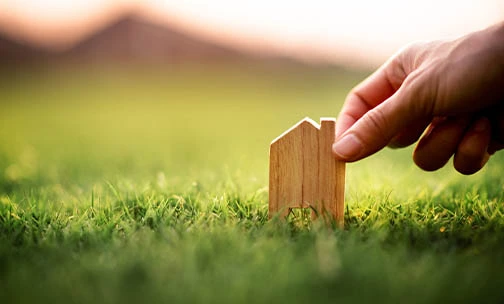 Man holding wooden home shaped miniature in the lawn