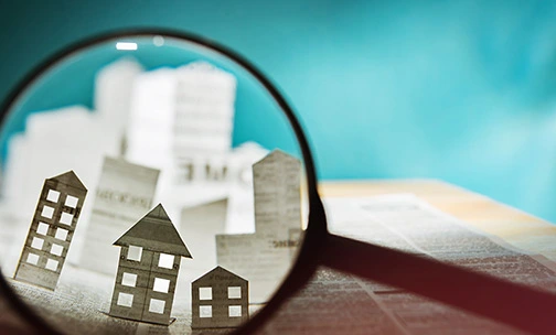 magnifying glass in front of paper homes