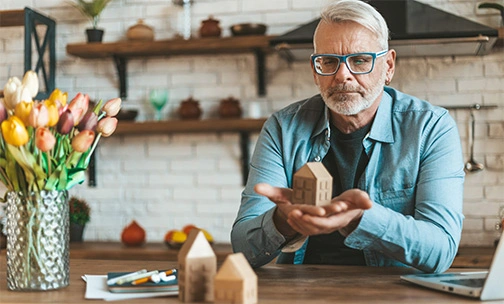 man at a table holding a wooden house