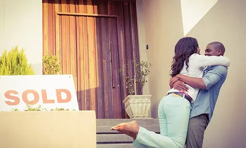 Couple hugging next to sold home