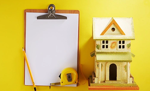 model house with blank clipboard and tape measure