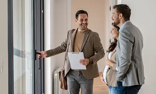 A young couple with a real-estate agent visiting an apartment for sale or for rent. Married couple buying an apartment. Real estate